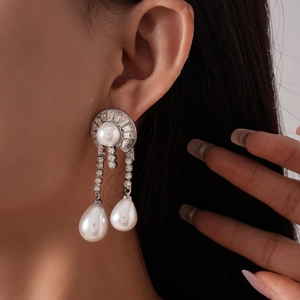 Detail of drop earrings with faux pearls and sparkling rhinestones on model
