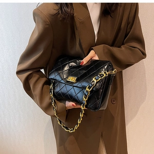 Close-up of quilted leather crossbody bag with gold chain strap on a brown blazer outfit
