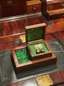 Macro view of walnut jewelry box with green carved glass lid and velvet interior