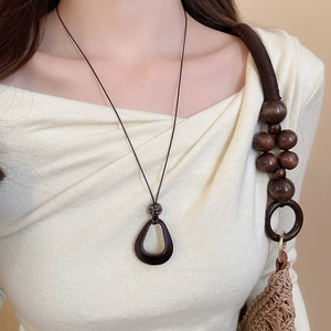Detail of a resin teardrop pendant on a wax cord styled with a minimalist knit sweater