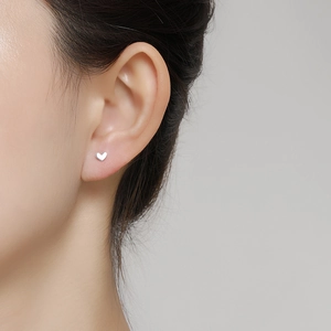 Close-up of minimalist S999 silver heart stud earring worn on ear for a delicate look