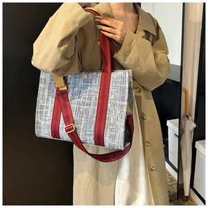 Detail of blue denim tote bag texture with red striped handle and golden buckle