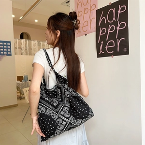 Model wearing a large black and white paisley canvas tote bag in a casual lifestyle setting