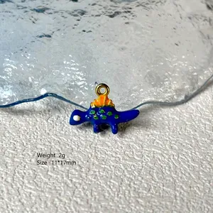 Macro shot of blue cartoon dinosaur enamel charm with gold loop for DIY jewelry