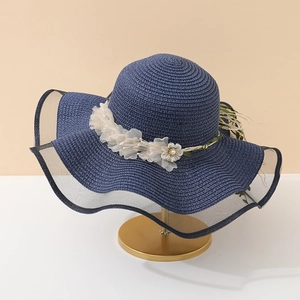 Détail d'un chapeau de soleil en paille bleu marine avec fleurs en organza et bord en résille