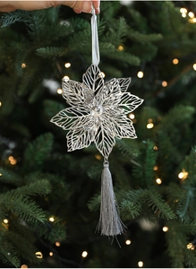 Detail of silver hollowed leaf ornament with grey tassel on a decorated Christmas tree