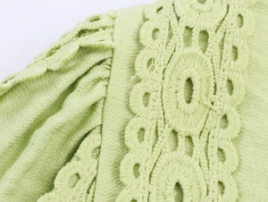 Detail of light green pleated fabric with intricate hollowed-out crochet lace texture