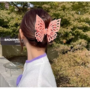 Detail view of a pink butterfly hair claw clip worn on a model in a natural setting