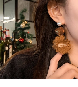 Close-up of elegant knitted flower and pearl earrings on a model in a warm festive setting