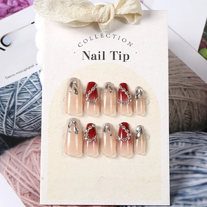 Close-up of red and nude gradient press-on nails with rhinestone and glitter decorations