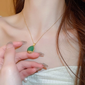 Close-up of elegant gold chain necklace with green teardrop gem in oriental style