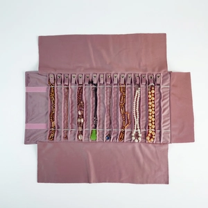 Pink velvet jewelry roll bag with multiple snaps for necklace and bracelet storage