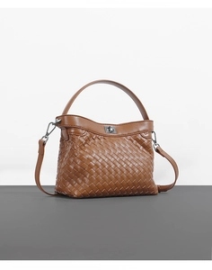 Detail of brown woven leather texture and metallic turn-lock on Kelly style handbag