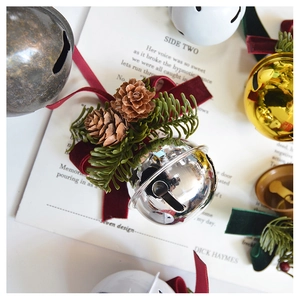 Close-up of silver Christmas bell with pine cones, needles and velvet ribbon bow