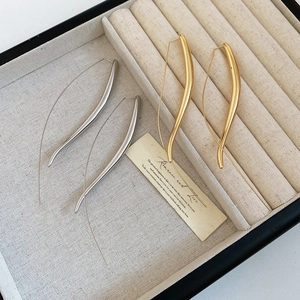 Polished gold and silver teardrop ear hooks on elegant fabric jewelry display