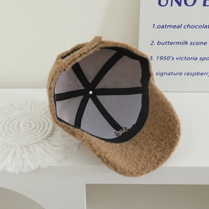 Detailed macro view of caramel plush lamb wool texture and cute bear embroidery on the cap