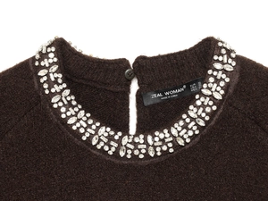 Macro view of crystal beaded neckline and velvet fabric on dark brown knit sweater
