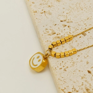 Gold-plated stainless steel square smiley pendant necklace on a textured stone base