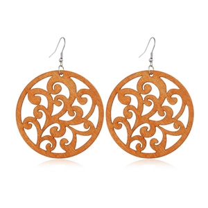Macro shot of circular hollow wooden earrings with floral scroll pattern and metal hooks