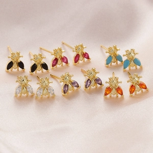 Detailed view of colorful bee stud earrings with crystal wings on pink silk fabric