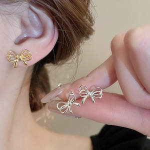 Close-up of elegant polished metal bow earrings in gold and silver finishes