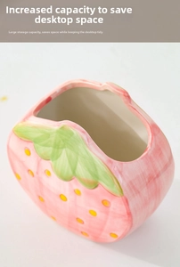 Macro view of large ceramic strawberry pen holder with pink glaze and green leaf detail