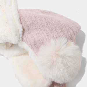 Pink knitted winter earflap hat with soft white faux fur lining and large pom-pom details