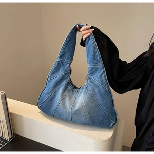 Détail de la texture en denim et des coutures contrastées sur le sac à bandoulière