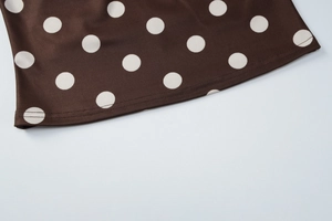 Dettaglio ravvicinato di tessuto marrone scuro a pois bianchi con cuciture sull'orlo