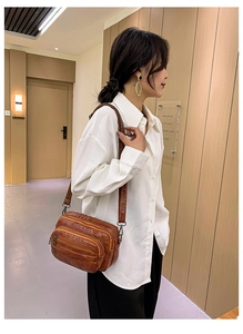 Vue détaillée du sac bandoulière marron vintage avec plusieurs poches zippées et texture