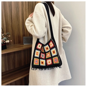 Close-up of handmade crochet bag with colorful granny squares and black fringe detail