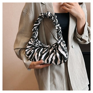 Detailed shot of zebra pattern cloud bag with pleated texture on a grey suit model