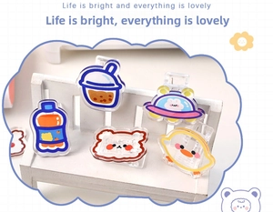 Macro shot of assorted acrylic cartoon clips featuring animals and snacks on a white bench
