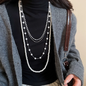 Detailed layered pearl necklace with silver chain on black sweater outfit