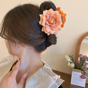 Gros plan sur une pince à cheveux rose en tissu orange ornant un chignon de cheveux bruns