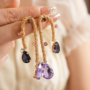 Close-up of vintage gold twisted earrings with purple and pink gemstones on model
