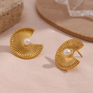 Detail of gold fan-shaped stud earrings with radiating texture and center pearl