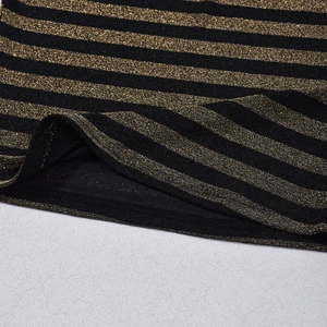 Primer plano de tela a rayas negras y doradas con brillo metálico y detalles de costura