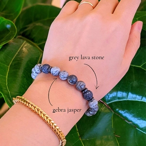 Close-up of natural grey lava stone and zebra jasper bead bracelet worn on wrist