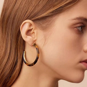 Close-up of vintage tortoiseshell resin C-shaped earrings with gold metal lining on a model