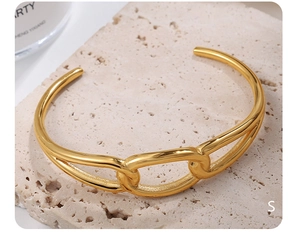 Macro shot of gold interlocking chain buckle on minimalist open cuff bracelet