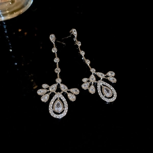 Macro shot of silver tassel earrings with teardrop zircons and fan-shaped leaf pendants