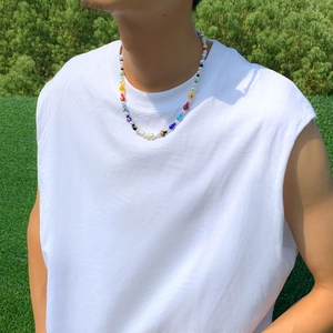 Close-up of a colorful beaded necklace with faux pearls worn by a male model outdoors
