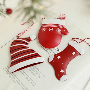 Dreiteiliges Metall-Weihnachtsanhänger-Set mit Mütze, Handschuh und Socke auf einem Buch