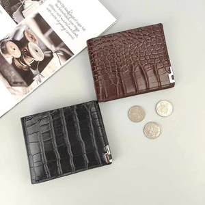 Detail of crocodile pattern leather wallets in black and brown with coins and magazine