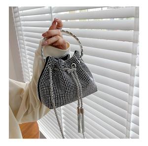 Detail of black mini bucket bag featuring sparkling rhinestones and metal ring handle