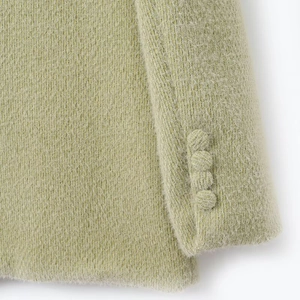 Detail van licht olijfgroene suède blazer met getextureerde stof en vier knopen