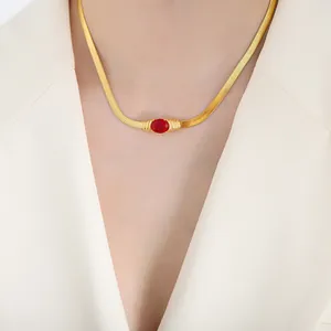 Elegant gold snake chain necklace featuring an oval red gemstone pendant on a model