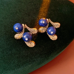 Detail of vintage gold leaf earrings with blue lapis beads and diamonds on green velvet