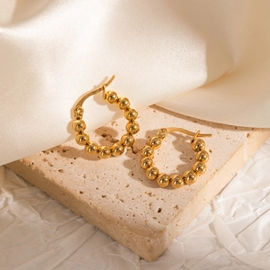 Detailed view of 18k gold plated beaded hoop earrings on elegant silk background